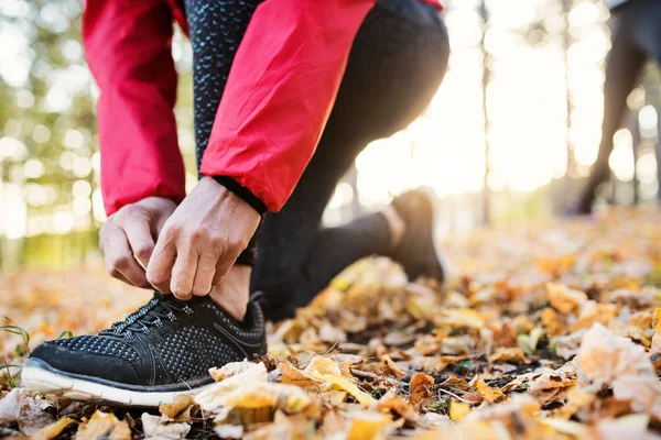 Una sección media de corredor femenino al aire libre en la naturaleza de otoño, atando cordones de zapatos . —  Fotos de Stock