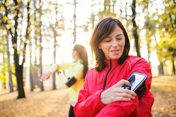 Kvinnliga löpare med smartphone utomhus i skogen i naturen, mättid. — Stockfoto