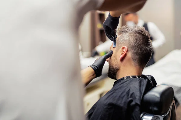 Un cliente uomo in visita dal parrucchiere e parrucchiere nel negozio di barbiere . — Foto Stock
