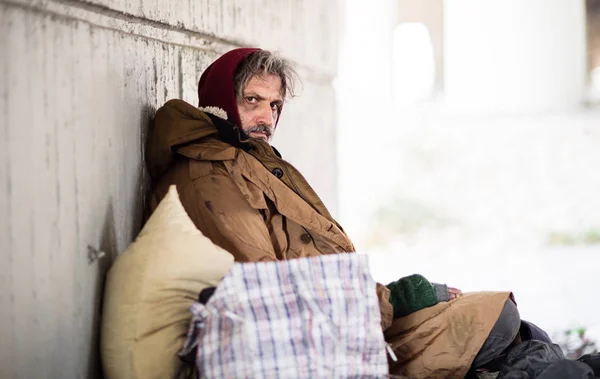 Una vista laterale del mendicante senzatetto seduto all'aperto, appoggiato a un muro. Copia spazio . — Foto Stock