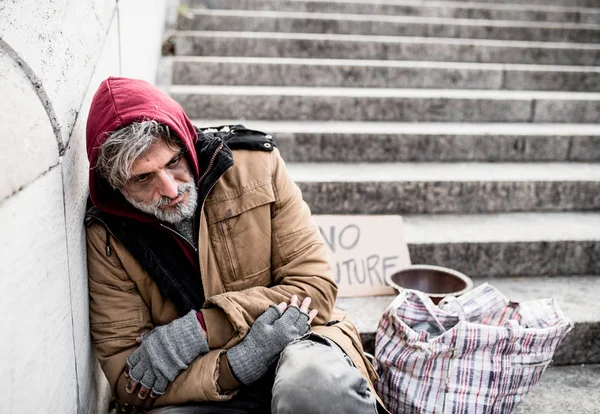 Żebrak bezdomny człowiek siedzi na zewnątrz, w mieście, prosząc o pieniądze darowizny. — Zdjęcie stockowe