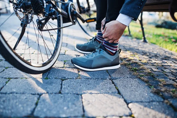 Средняя часть пригородного с велосипедом, путешествующего с работы в городе, завязывающего шнурки . — стоковое фото
