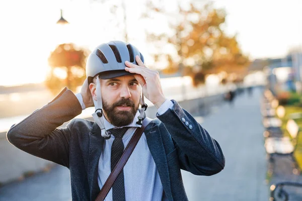 Empresario viajando a casa desde el trabajo en la ciudad, poniéndose un casco de bicicleta . — Foto de Stock