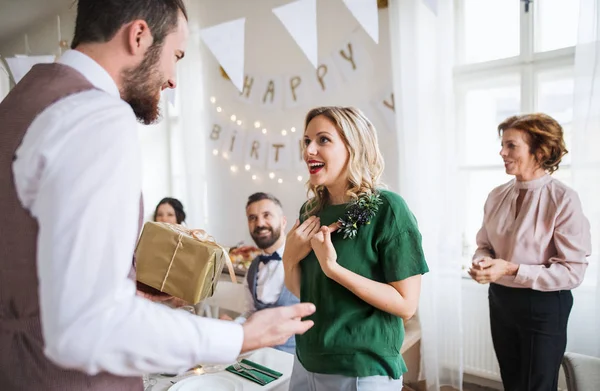 Un hombre dando un regalo a una joven sorprendida en una fiesta de cumpleaños familiar . —  Fotos de Stock