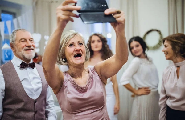 Egy magas rangú nő férjét esküvő vagy születésnapi party, figyelembe véve a selfie smartphone. — Stock Fotó