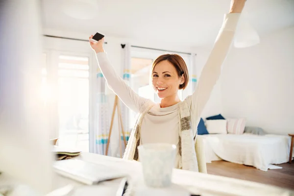 Uma jovem feliz com braços estendidos dentro de casa, trabalhando em um escritório em casa . — Fotografia de Stock