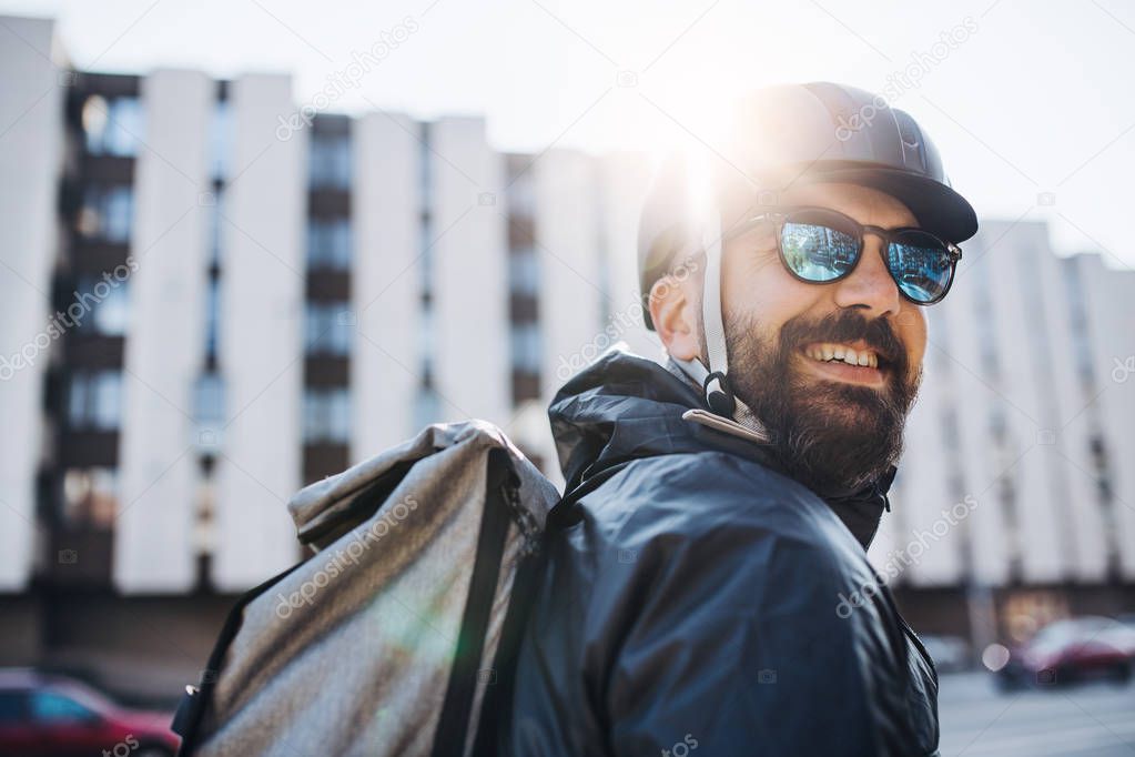Male courier with sunglasses delivering packages in city.