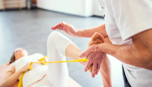 Fisioterapista anziano non riconoscibile che lavora con una paziente donna . — Foto Stock