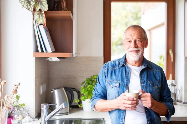 Sênior segurando uma xícara de café na cozinha . — Fotografia de Stock