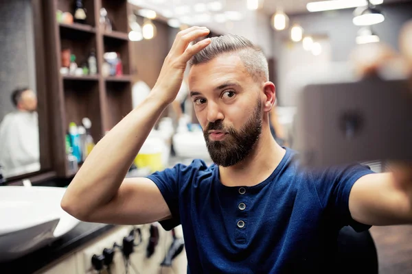 Hipster-Mann-Klient im Friseursalon macht lustige Gesichter, wenn er Seflie nimmt. — Stockfoto