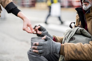 Kadın şehirde oturan evsiz dilenci adam için para veren bir midsection görünümünü.