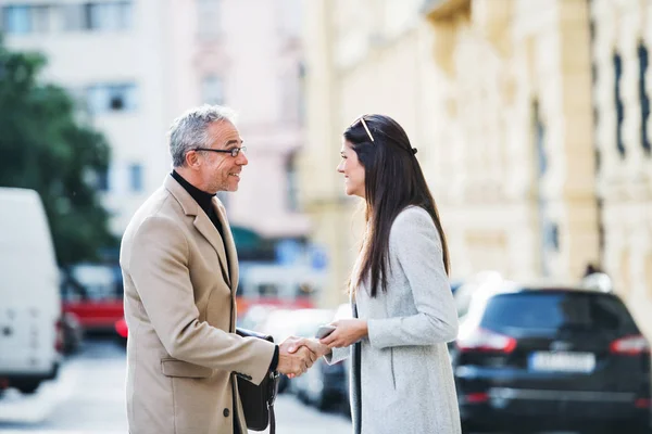 Man and woman business partners standing outdoors in city of Prague, shaking hands. — Stock Photo, Image