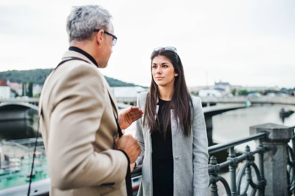 Man och kvinna affärspartners walking av en flod i staden Prag, talar. — Stockfoto