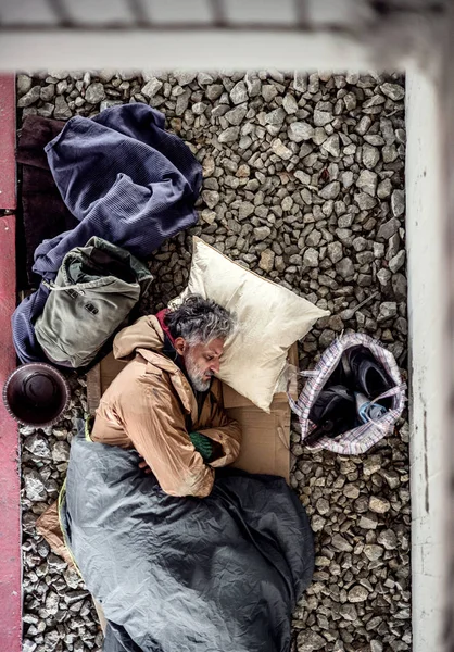 Pohled shora bezdomovec žebrák muž ležící na zemi venku v městě, spí. — Stock fotografie