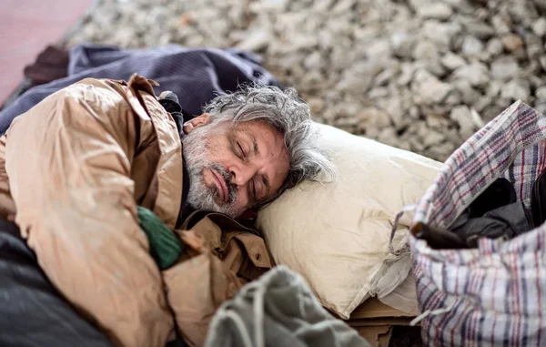 Homeless beggar man lying on the ground outdoors in city, sleeping. — Stock Photo, Image