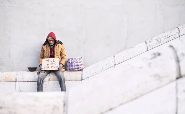 Homem mendigo sem-abrigo sentado na cidade segurando cartaz. Espaço de cópia . — Fotografia de Stock