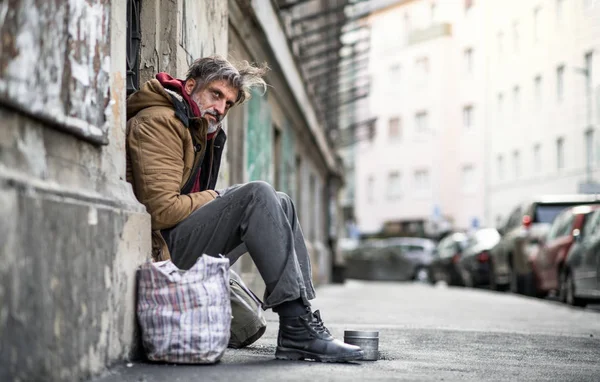 Un mendicante senzatetto seduto all'aperto in città, che chiede una donazione di denaro . — Foto Stock
