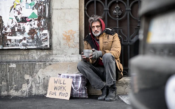Açık havada para bağış için soran şehirde oturan evsiz dilenci adam. — Stok fotoğraf