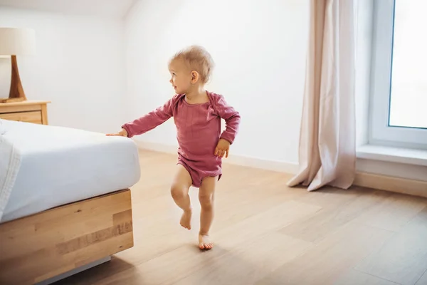 Una niña pequeña caminando dentro de un dormitorio . — Foto de Stock