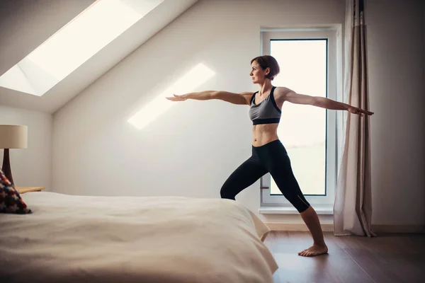 Sidovy av ung kvinna gör övning inomhus i ett sovrum. Kopiera utrymme. — Stockfoto