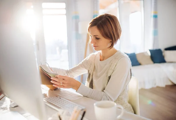 Une jeune femme heureuse à l'intérieur, travaillant dans un bureau à domicile . — Photo