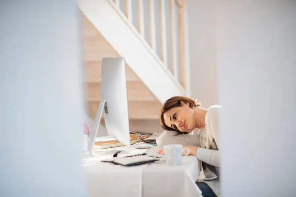 Uma jovem cansada dentro de casa, trabalhando em um escritório em casa . — Fotografia de Stock