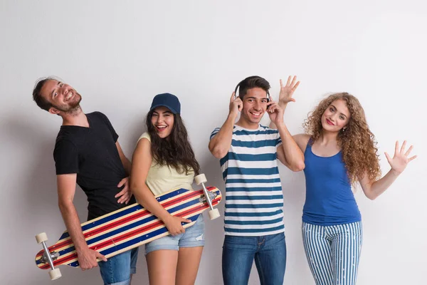 Retrato de alegre grupo de amigos con longboard de pie en un estudio . —  Fotos de Stock