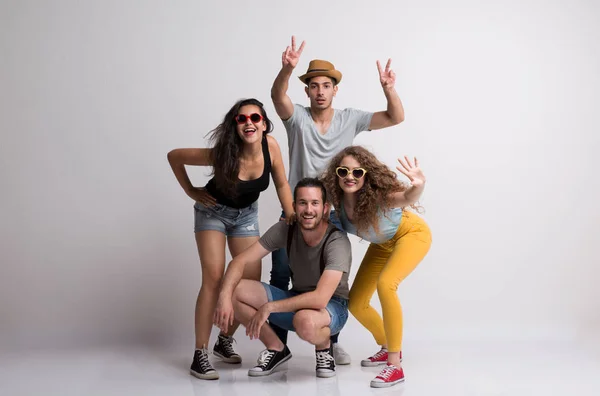 Portret van vrolijke jonge groep vrienden met hoed en zonnebril permanent in een studio. — Stockfoto