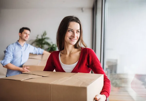 Jeune couple avec des boîtes en carton se déplaçant dans une nouvelle maison . — Photo