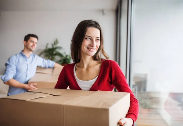 Pareja joven con cajas de cartón moviéndose en un nuevo hogar . — Foto de Stock