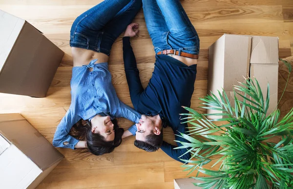 Una vista superior de pareja joven con cajas de cartón moviéndose en un nuevo hogar . — Foto de Stock