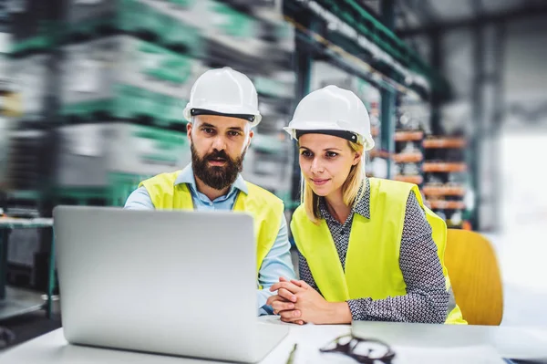 Um retrato de um homem industrial e mulher engenheiro com laptop em uma fábrica, trabalhando . — Fotografia de Stock