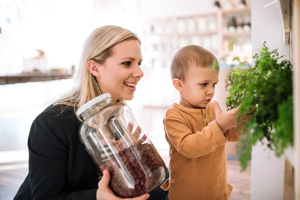 Una joven con un niño pequeño comprando comestibles en una tienda de basura cero . —  Fotos de Stock