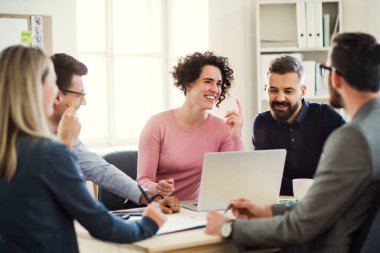 Grup Toplantısı modern bir ofiste masa etrafında oturan genç iş adamları.