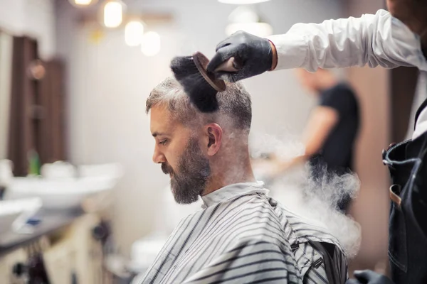 Клиент хипстера, посещающий парикмахера и парикмахера, курящий трубку . — стоковое фото