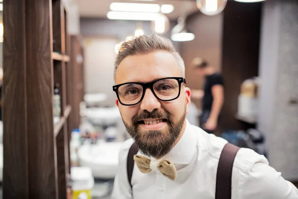 Portrait d'un bel homme hipster client debout dans un salon de coiffure . — Photo