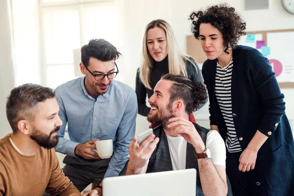 Groupe de jeunes entrepreneurs avec ordinateur portable travaillant ensemble dans un bureau moderne . — Photo