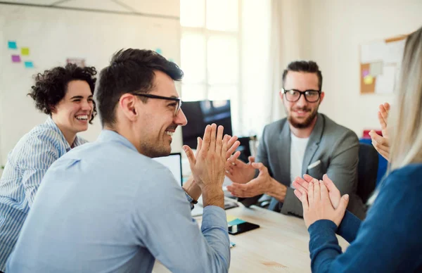 Grupo de jóvenes empresarios sentados alrededor de la mesa en una oficina moderna, teniendo reunión . — Foto de Stock