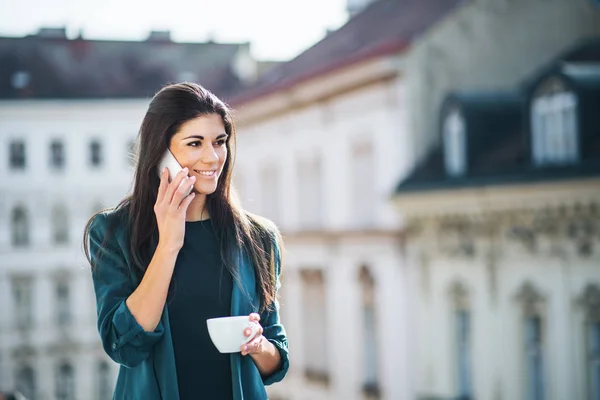 Junge Geschäftsfrau mit Smartphone steht auf einer Terrasse vor einem Büro in der Stadt. — Stockfoto