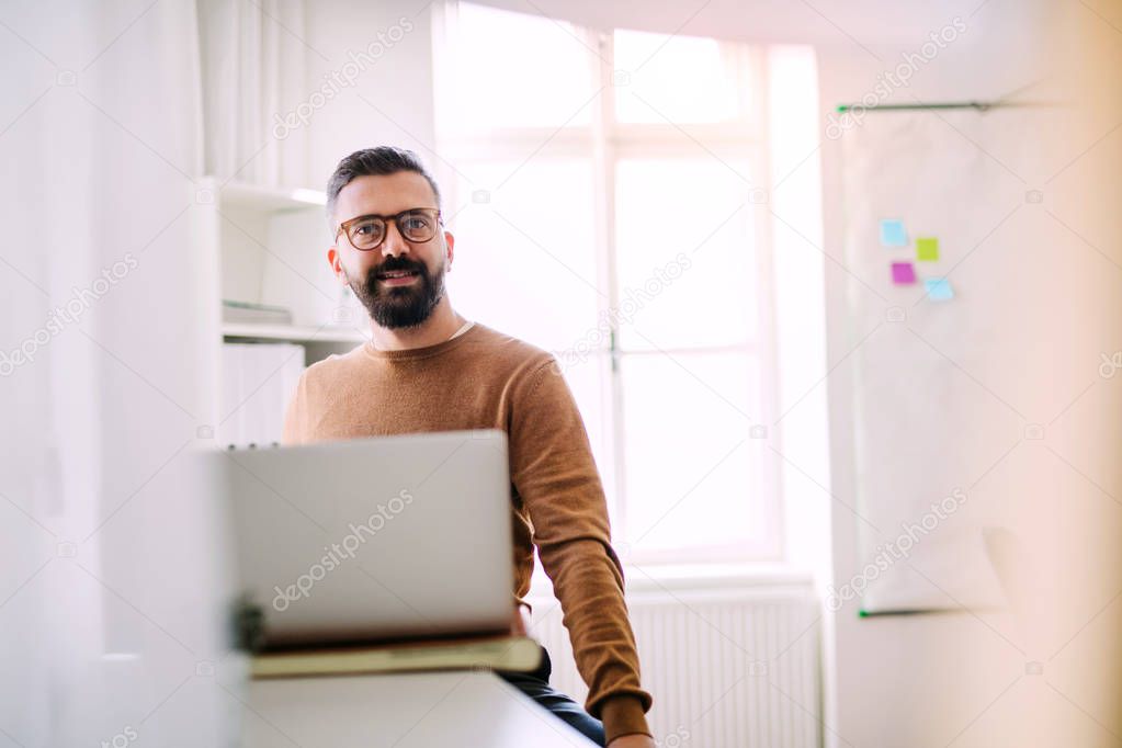 Mature hipster businessman with laptop working in a modern office.