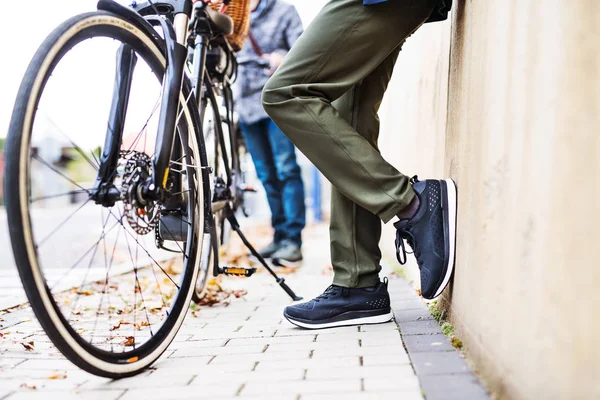 Seniorpaar mit Elektrofahrrädern steht im Freien auf einer Straße in der Stadt. — Stockfoto