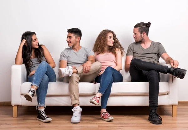 Retrato de jovem grupo de amigos sentados em um sofá em um estúdio, conversando . — Fotografia de Stock
