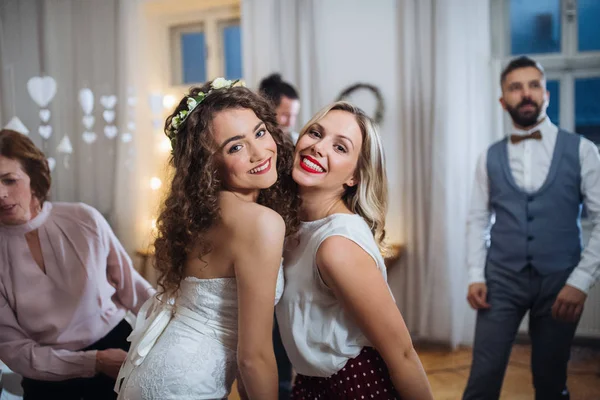 Uma jovem noiva e sua amiga posando em uma recepção de casamento, dançando . — Fotografia de Stock