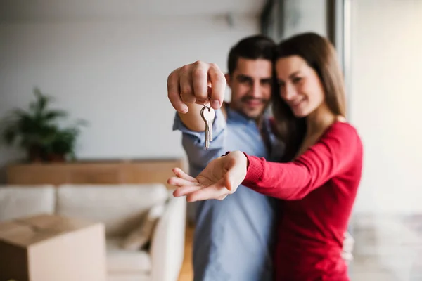 Una pareja joven con una llave y cajas de cartón moviéndose en un nuevo hogar . —  Fotos de Stock