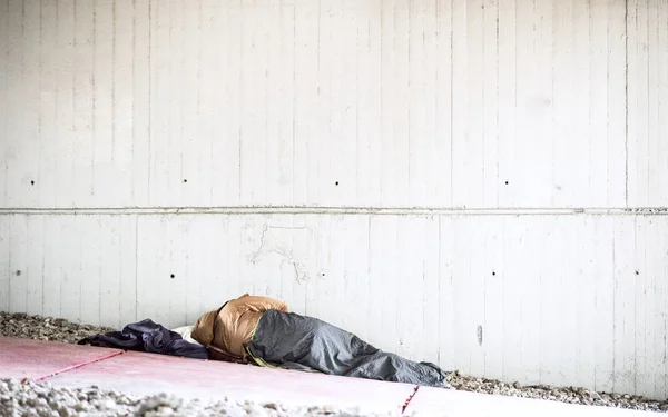 Een achteraanzicht van dakloze bedelaar man liggend op de grond buiten in de stad, slapen. — Stockfoto