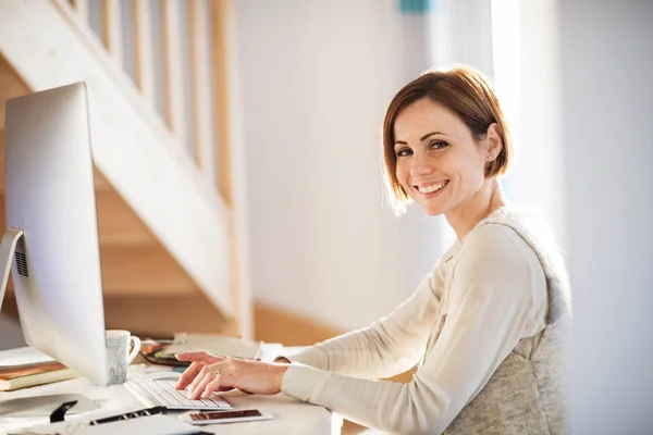 Une jeune femme heureuse à l'intérieur, travaillant dans un bureau à domicile . — Photo