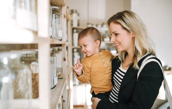 En ung kvinna med ett barn pojke att köpa dagligvaror i noll avfall shop. — Stockfoto