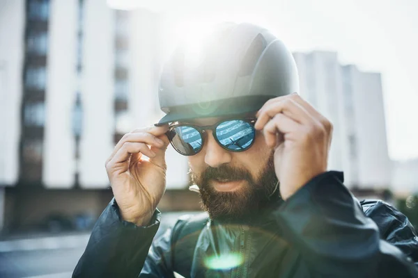 Mensageiro de bicicleta masculino com capacete colocando óculos de sol na cidade . — Fotografia de Stock