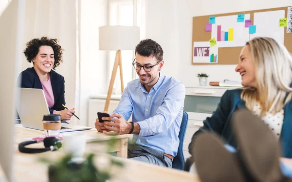 Gruppen av unga företagare med smartphone som arbetar tillsammans i ett modernt kontor. — Stockfoto