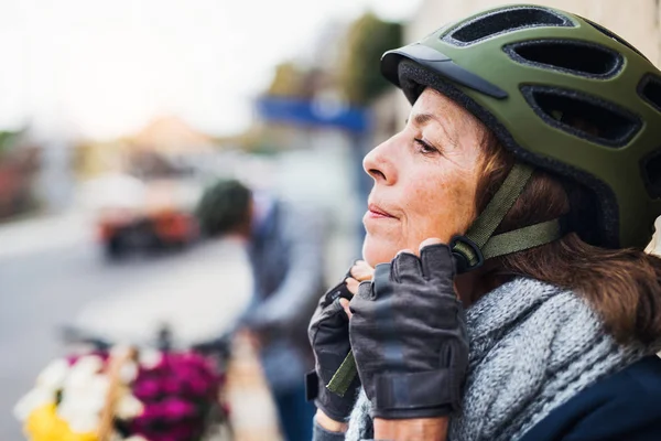 Активная пожилая женщина стоит на улице в городе, надевает велосипедный шлем. Копирование пространства . — стоковое фото